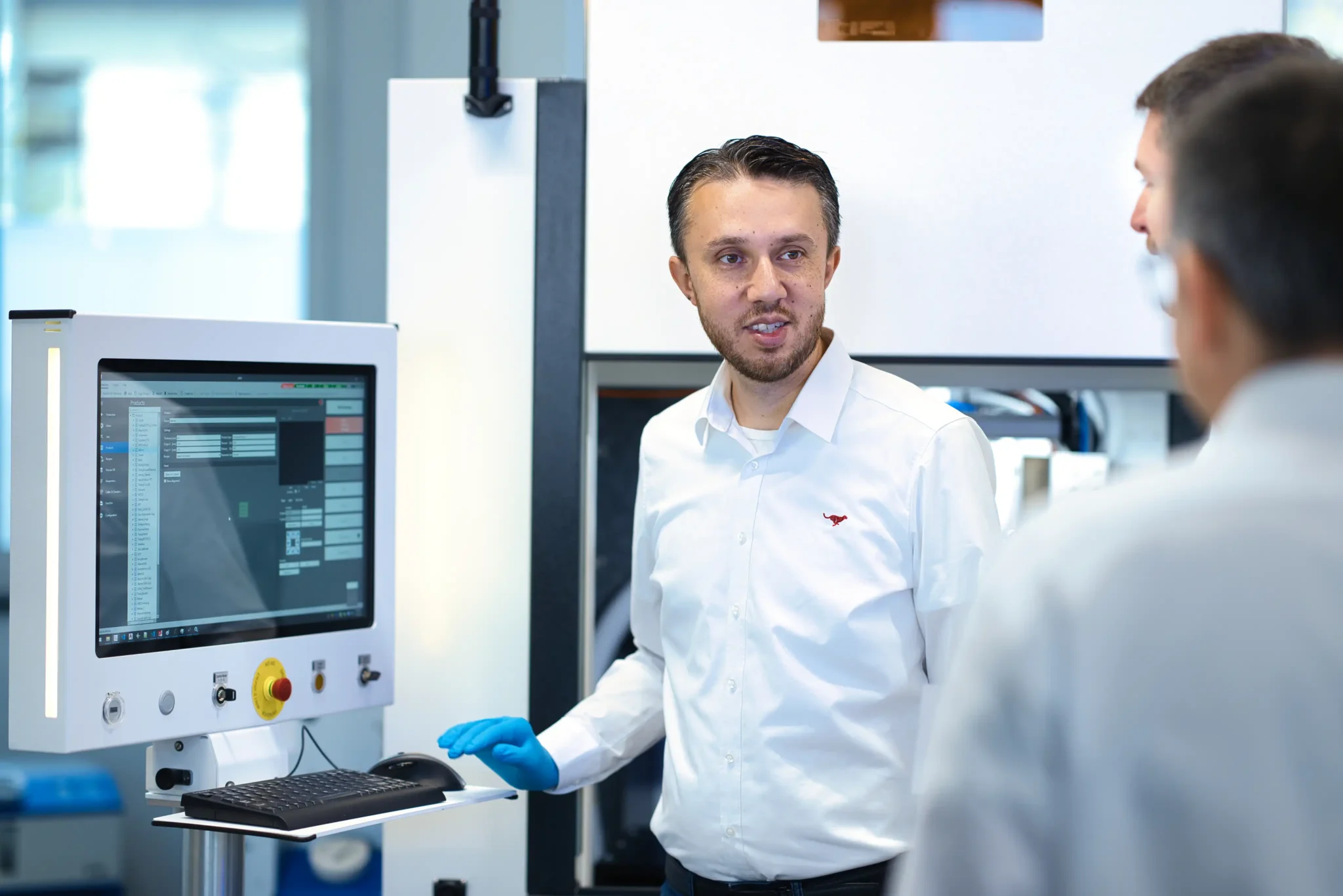 Two application specialists discussing a sample beside a laser system