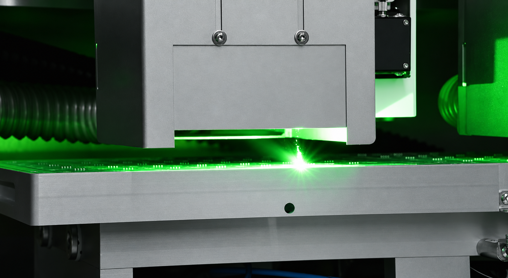Laser processing head separating a PCB panel with a green laser beam